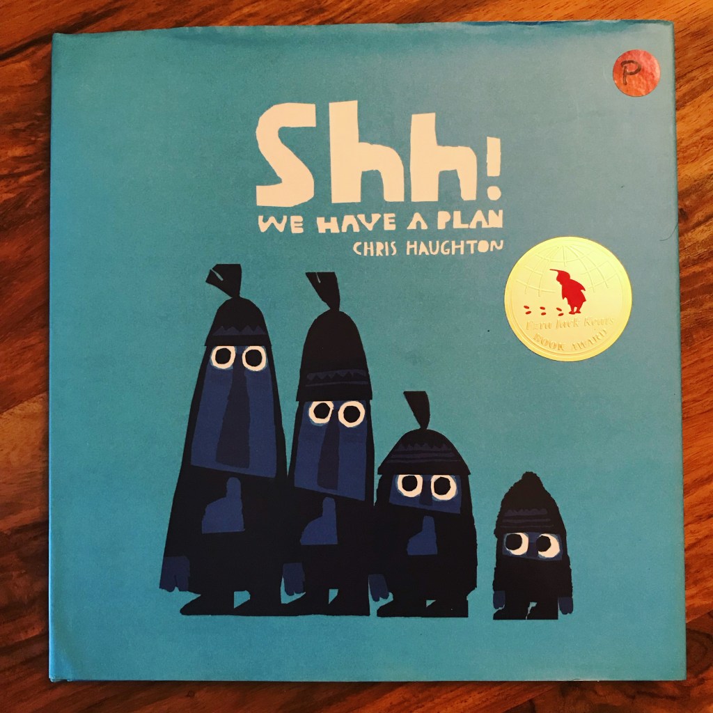 A blue book cover with the title "Shh! We Have a Plan!" written across the top in white letters. There are 4 character silhouettes with white eyes, the fourth is the smallest and is looking sideways at the other three. The book has a gold Ezra Jack Keats award sticker.